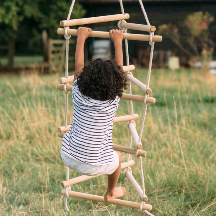 child playing on plum wooden rope ladder