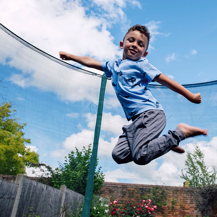 child jumping on plum trampoline with enclosure 