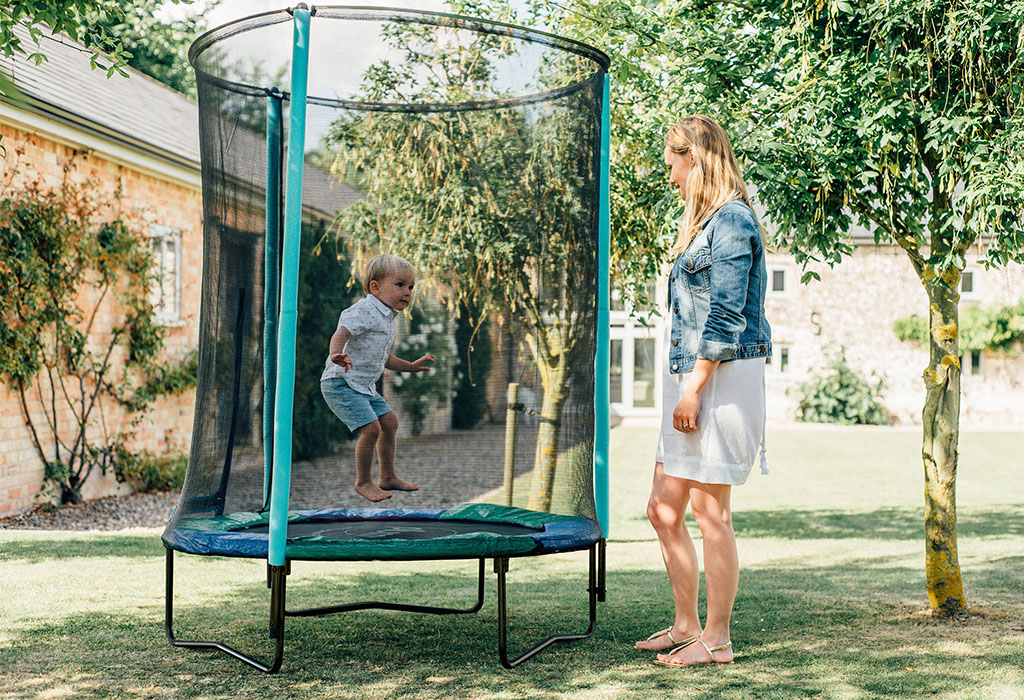 child jumping on trampoline with parent watching