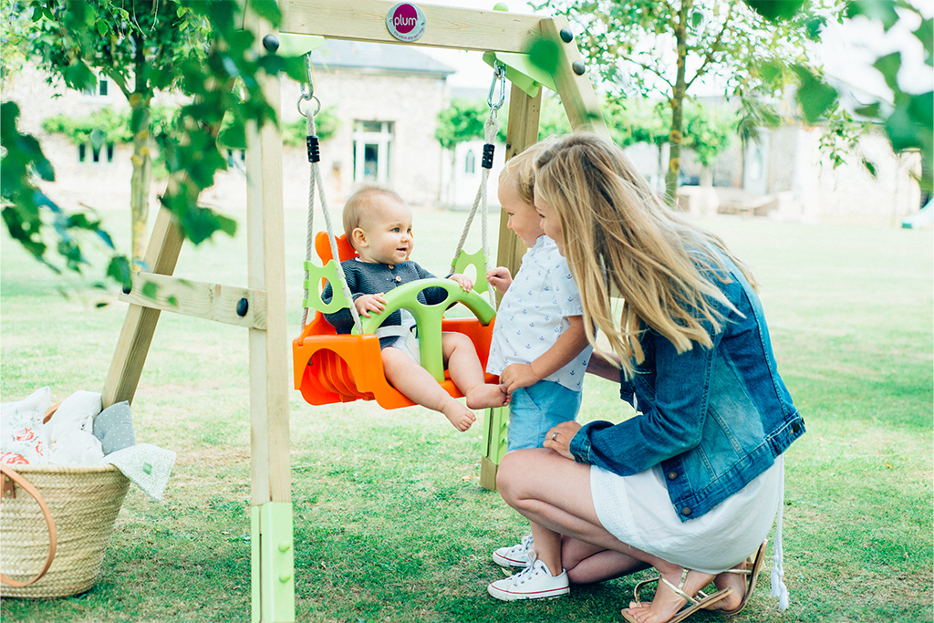 baby in wooden plum swing with family