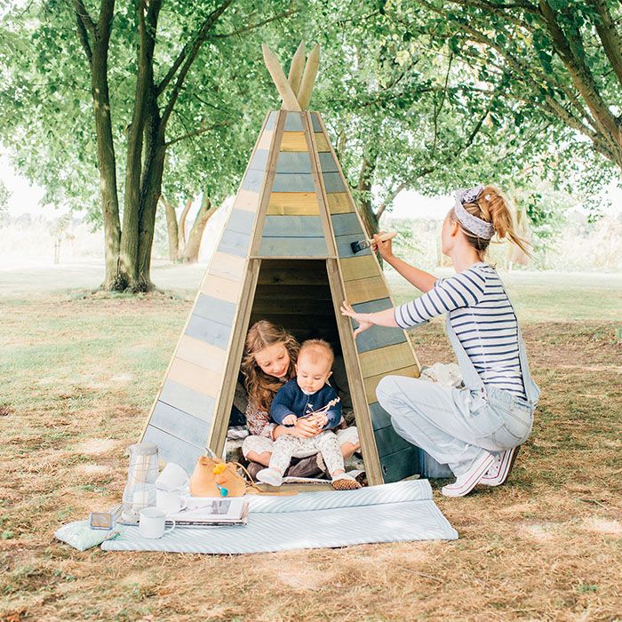 parent and children playing in wooden tee pee